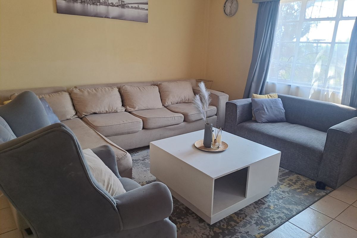 A comfortable living room featuring tiled flooring and a large window that allows for natural light.