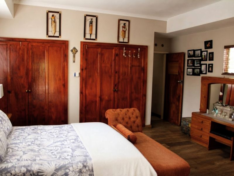 A bedroom featuring built-in wooden cupboards, laminate flooring, and coved ceiling details.