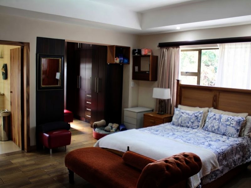 Spacious bedroom featuring built-in cupboards, a recessed ceiling, and an adjoining en-suite bathroom with tiled flooring throughout.