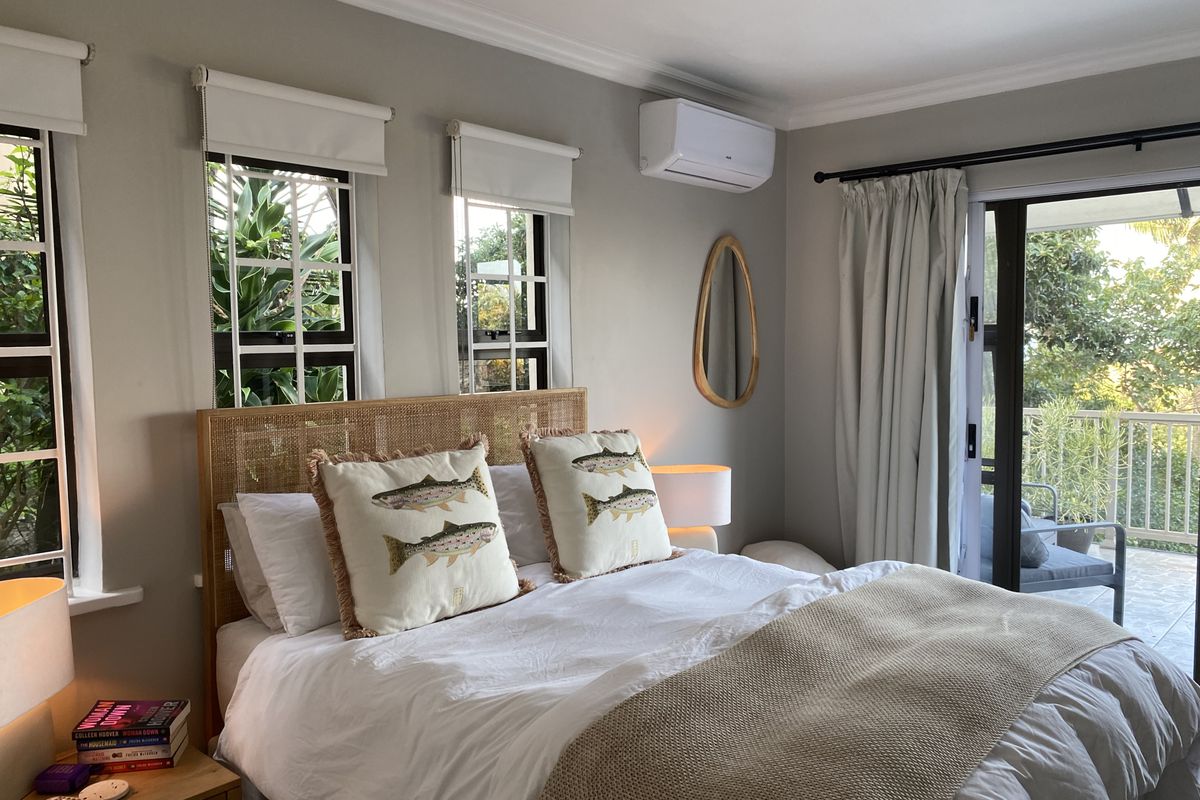 A well-maintained bedroom featuring a split-system air conditioner, ceiling fan, and sliding glass door access to an outdoor balcony.