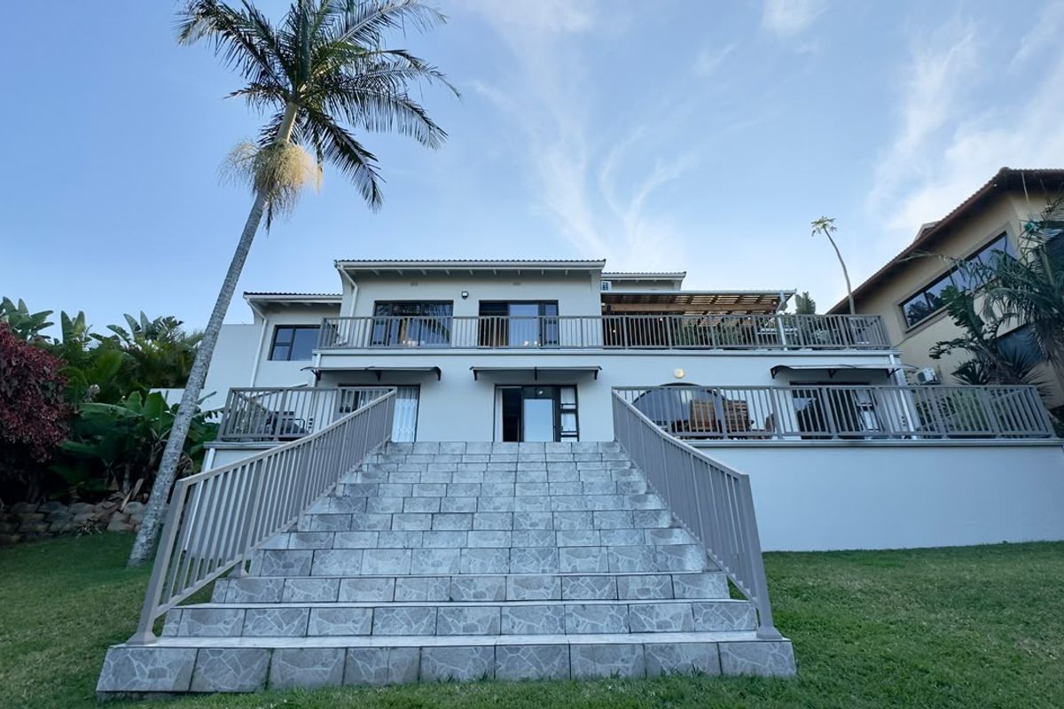 Rear elevation of the house featuring a large tiled staircase leading to a spacious balcony and terrace area with metal balustrades.