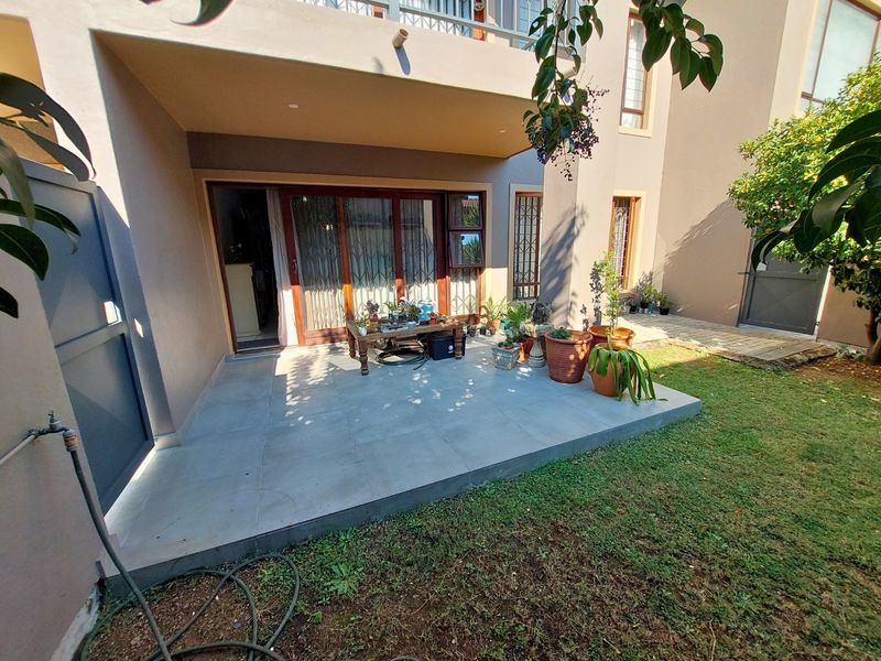 A covered patio area featuring tiled flooring, recessed lighting, and direct access to the garden through sliding glass doors.