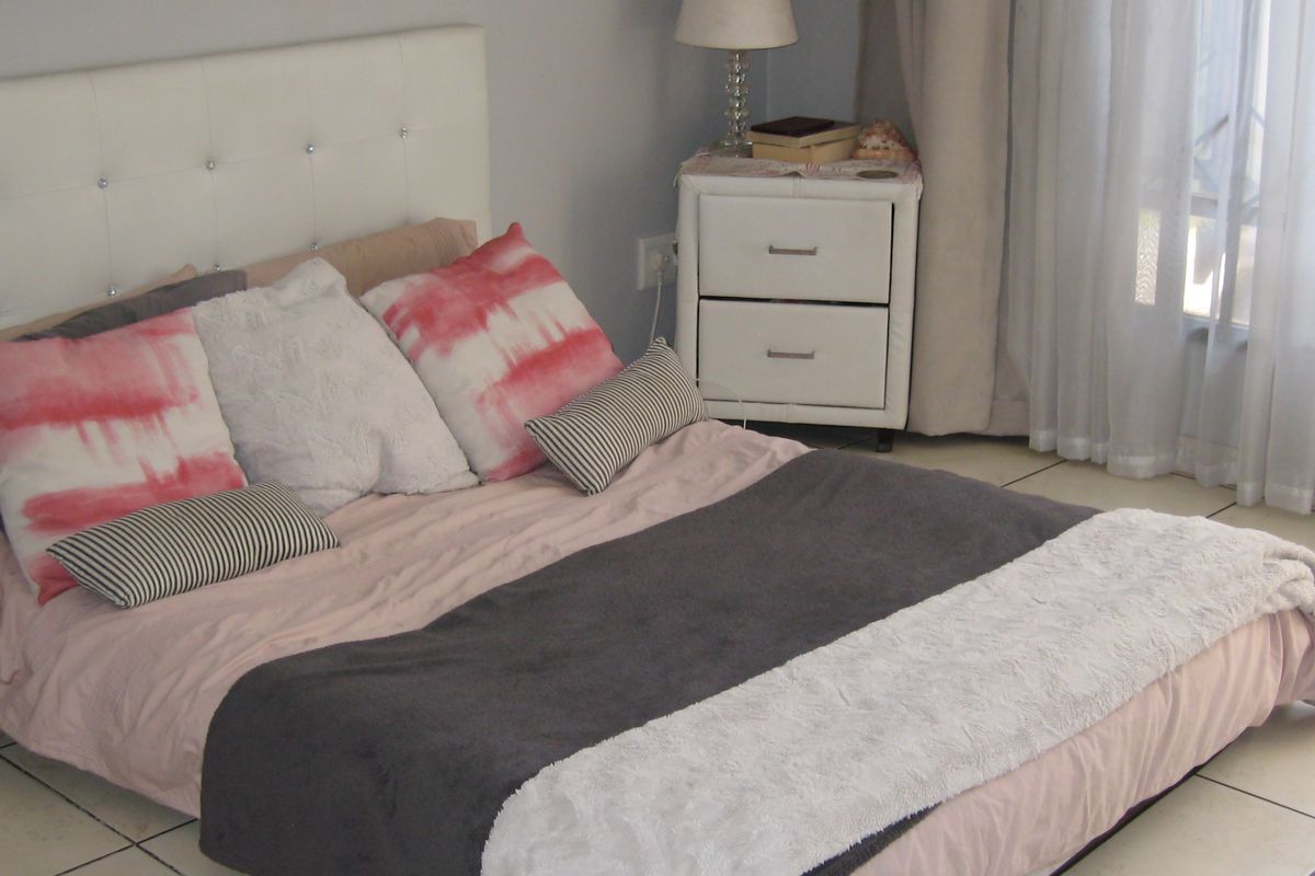 A bedroom featuring tiled flooring and neutral wall finishes, providing a functional space with natural light access through window treatments.