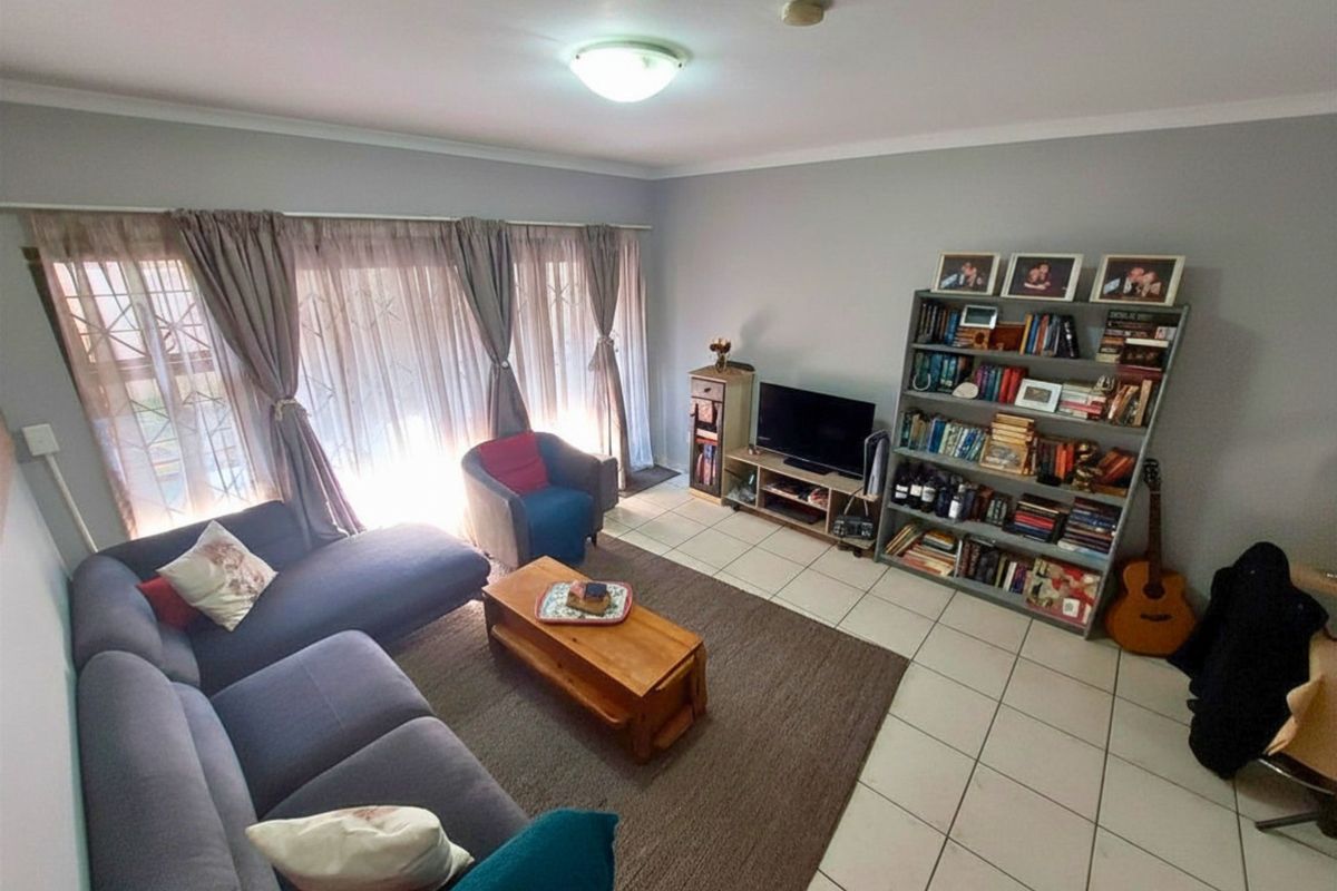 A living room featuring tiled flooring and a security gate over the window, providing a functional and comfortable space.