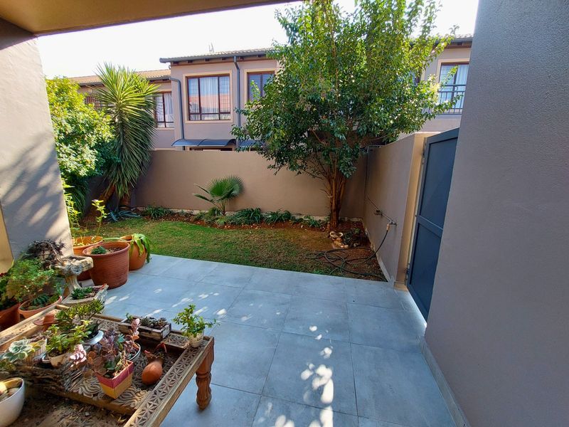 A private, paved patio area featuring a small garden, boundary wall, and direct access gate, perfect for outdoor relaxation.