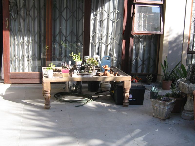 A paved outdoor patio area featuring sliding security gates and access to the interior, providing a functional space for outdoor living.