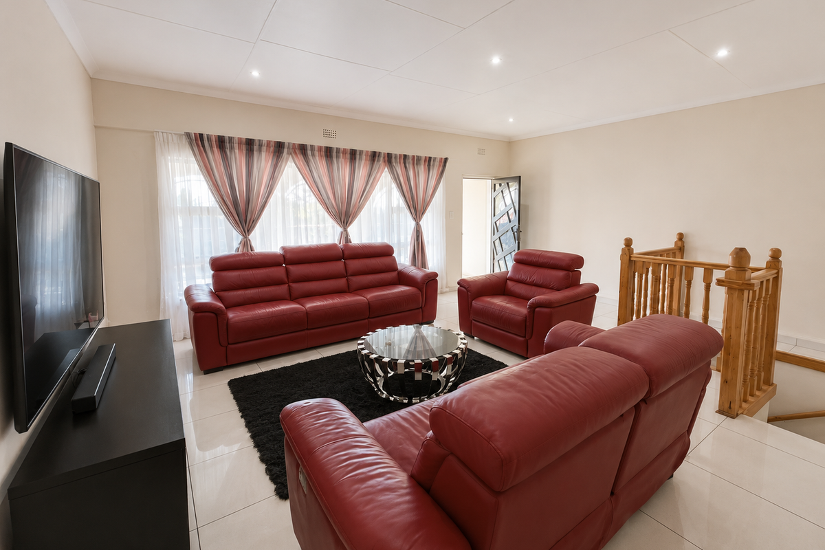 Spacious living room featuring neutral tiled flooring, recessed downlighting, and a wooden staircase balustrade, providing a bright and open atmosphere.
