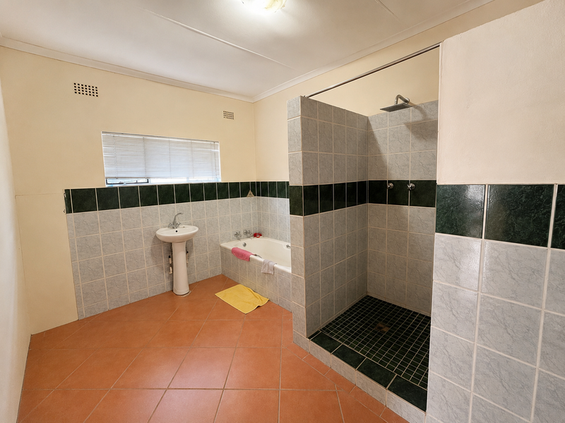 Spacious bathroom featuring a walk-in shower, built-in bathtub, and pedestal basin with tiled finishes throughout.