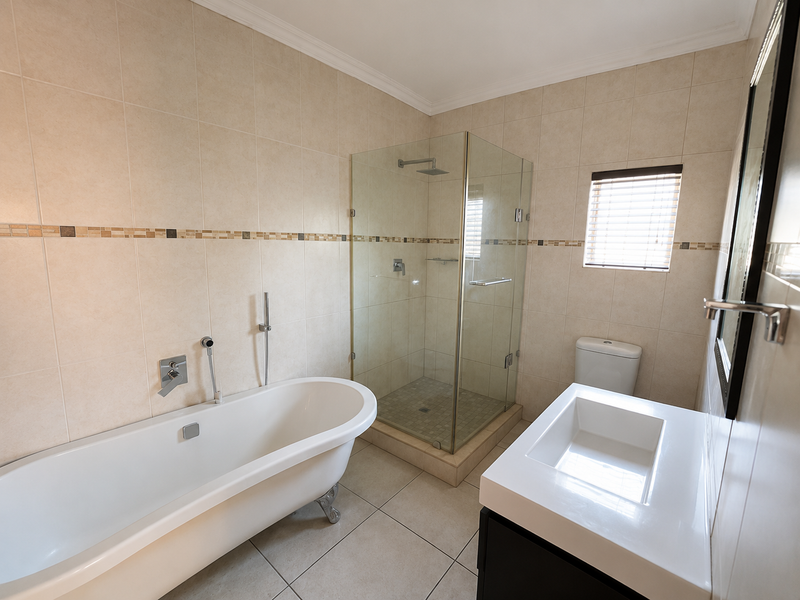 Modern bathroom featuring a freestanding bathtub, glass-enclosed shower, wall-mounted basin, and neutral tiled finishes throughout.
