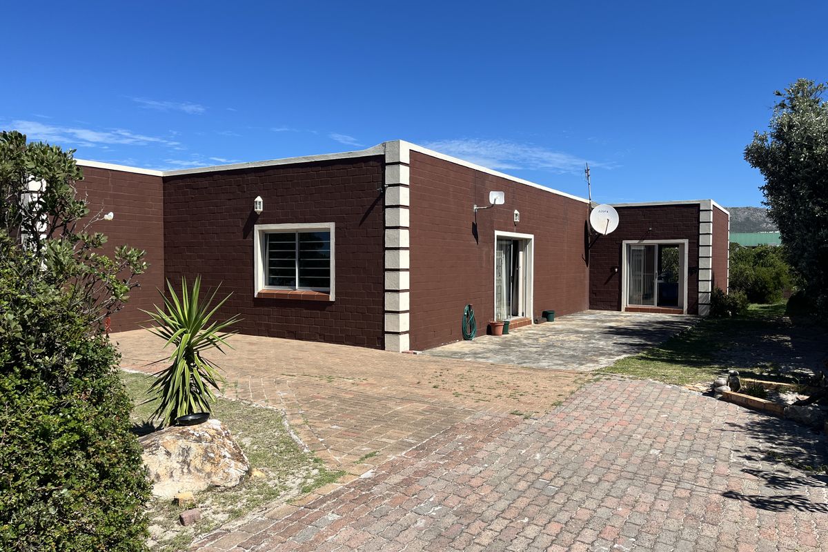 Rear view of the property featuring a paved patio area, brick driveway, and sliding glass door access to the home.