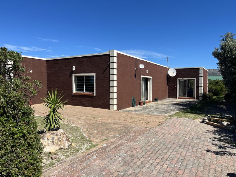 Rear view of the property featuring a paved patio area, brick driveway, and sliding glass door access to the home.