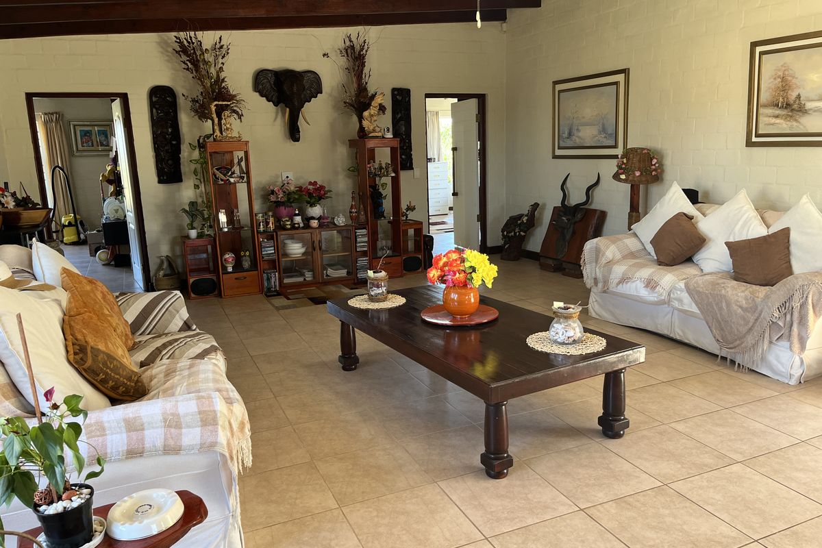 Spacious living room featuring exposed timber ceiling beams, tiled flooring, and painted brick walls, offering a warm and traditional aesthetic.