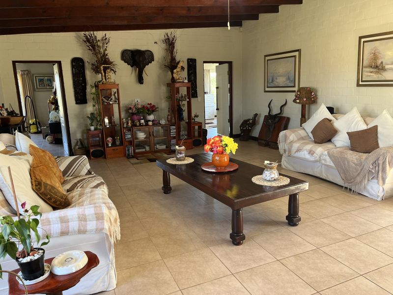 Spacious living room featuring exposed timber ceiling beams, tiled flooring, and painted brick walls, offering a warm and traditional aesthetic.