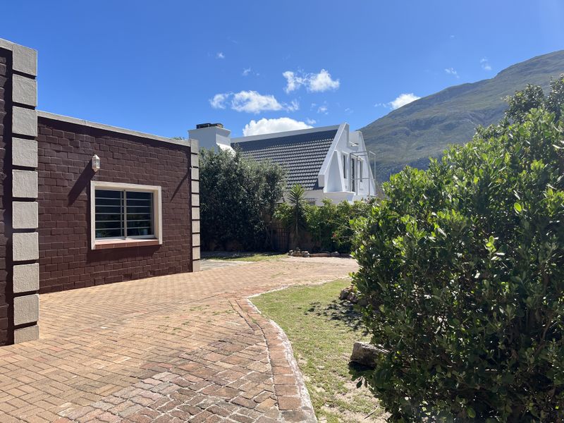 A view of the rear exterior area featuring brick paving, a landscaped garden, and a clear view of the surrounding mountain landscape.