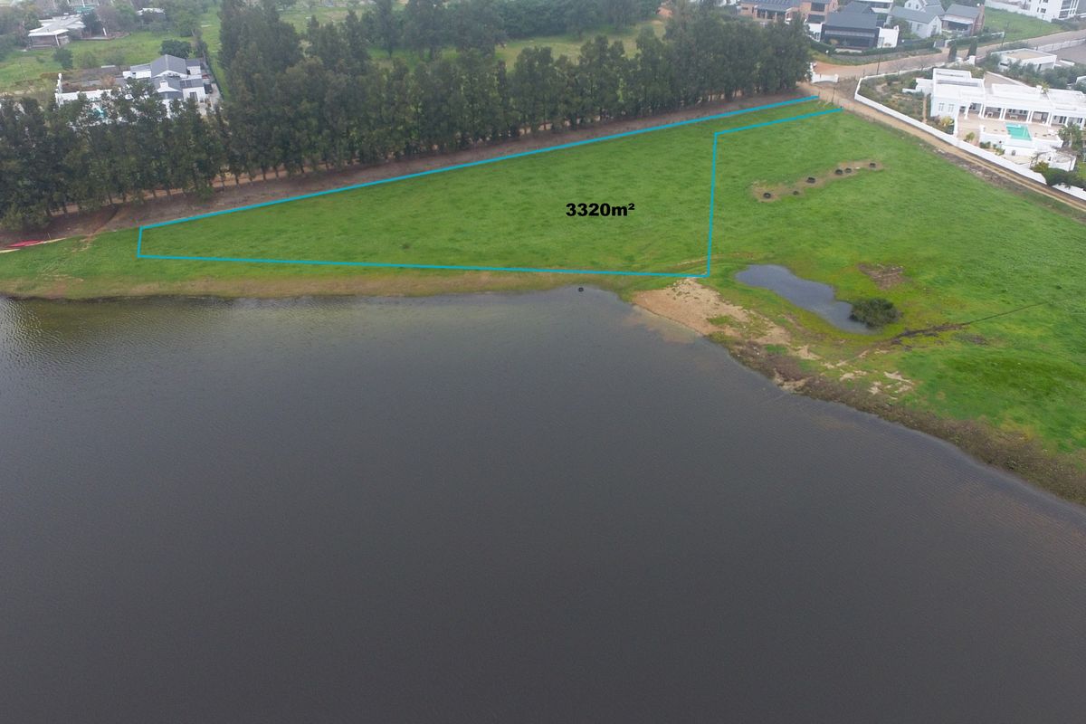 Aerial view of a 3320m2 vacant residential plot situated directly along the waterfront, offering expansive views and a natural landscape.