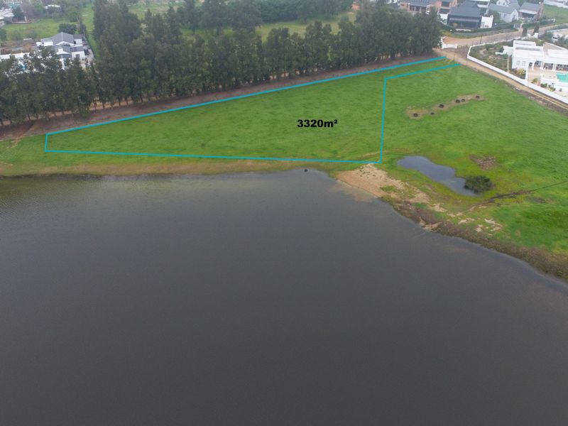 Aerial view of a 3320m2 vacant residential plot situated directly along the waterfront, offering expansive views and a natural landscape.