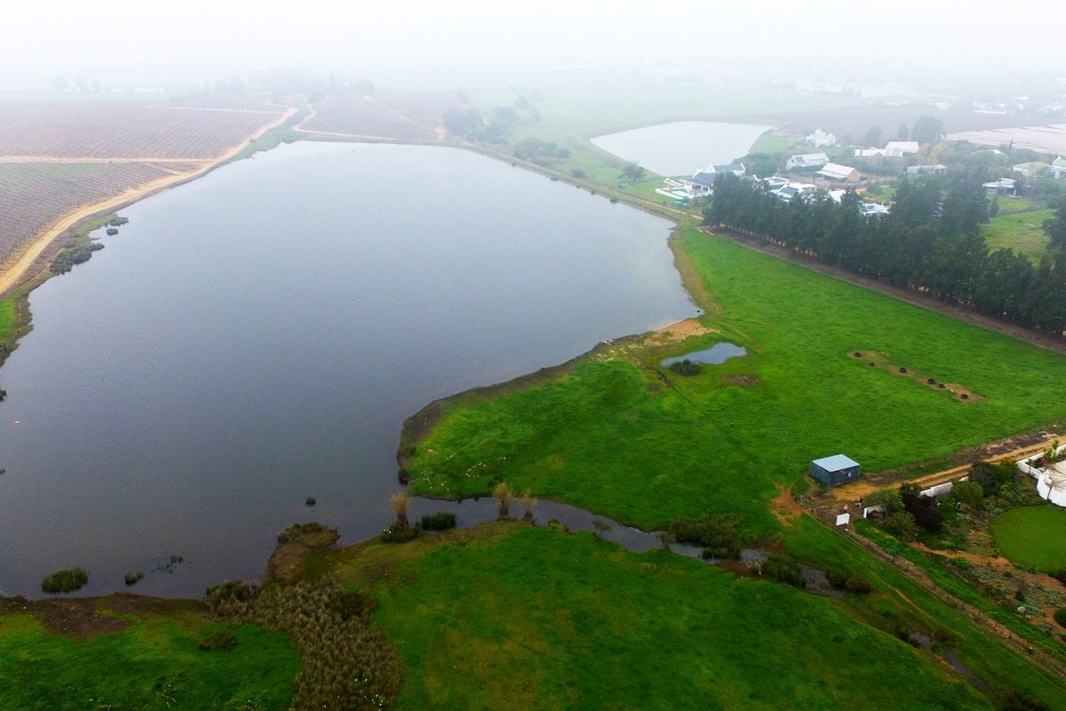 Aerial view of a large dam and surrounding green pasture land, showcasing the expansive rural landscape and natural water features of the property.