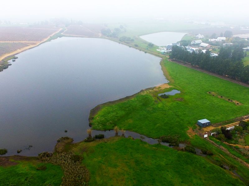 Aerial view of a large dam and surrounding green pasture land, showcasing the expansive rural landscape and natural water features of the property.