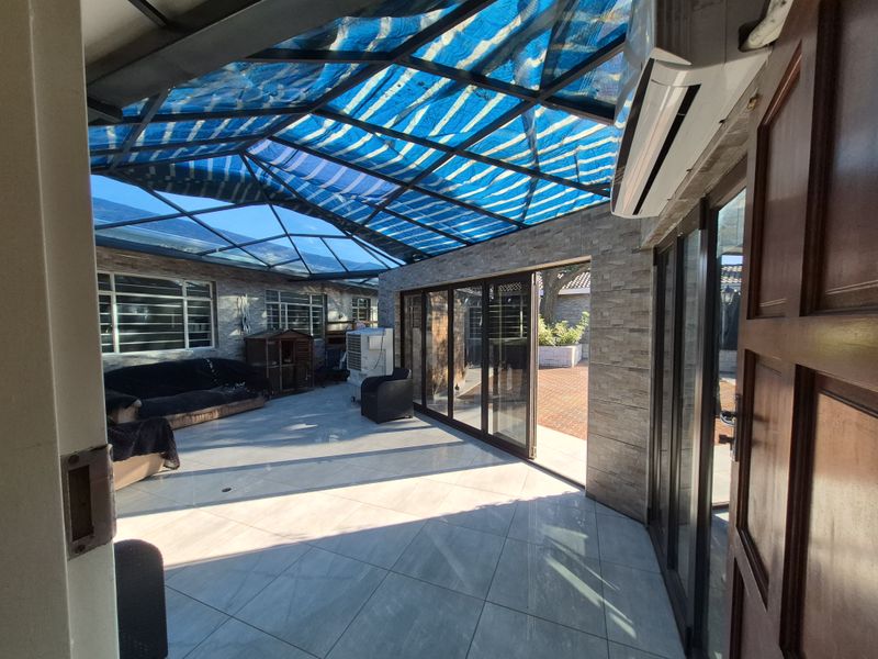 Enclosed patio area featuring stone-clad walls, tiled flooring, and a translucent roof structure, providing a versatile indoor-outdoor living space.