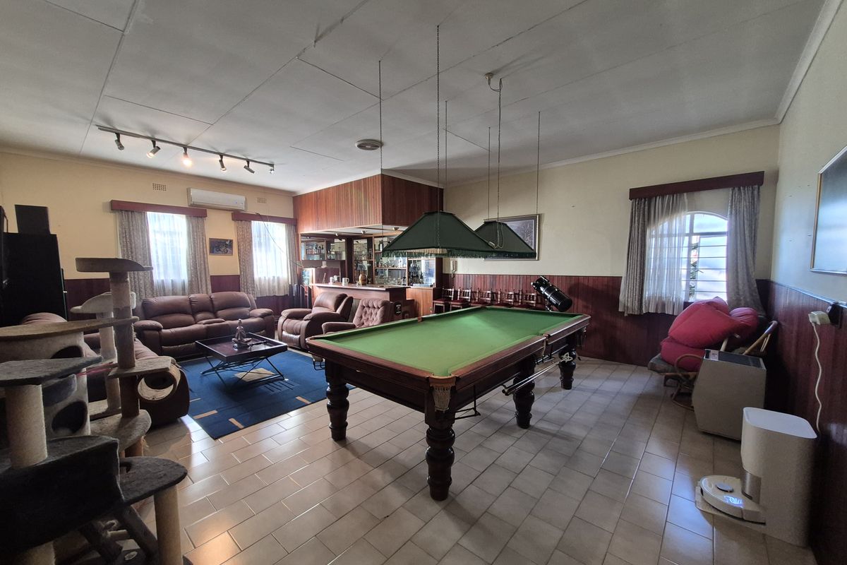 Spacious living area featuring a built-in bar, tiled flooring, timber wall paneling, and split-system air conditioning, offering a versatile entertainment space.