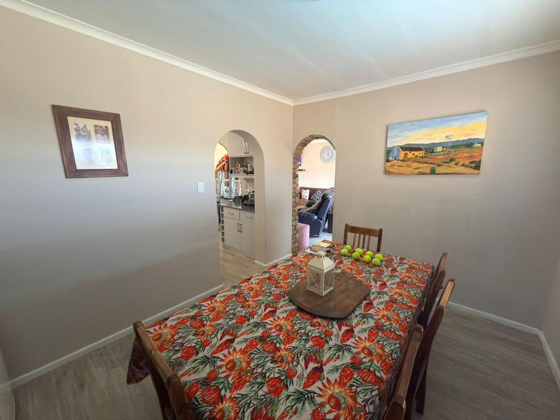 Dining room featuring laminate flooring and arched doorways leading to adjacent living and kitchen areas.