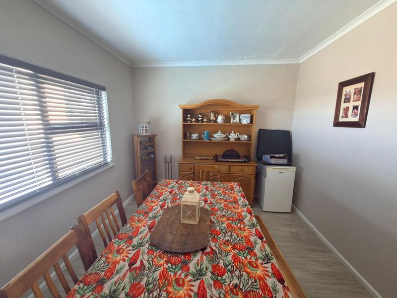 A functional dining room featuring laminate flooring, coving, and venetian blinds, with visible ceiling plaster cracks requiring maintenance.