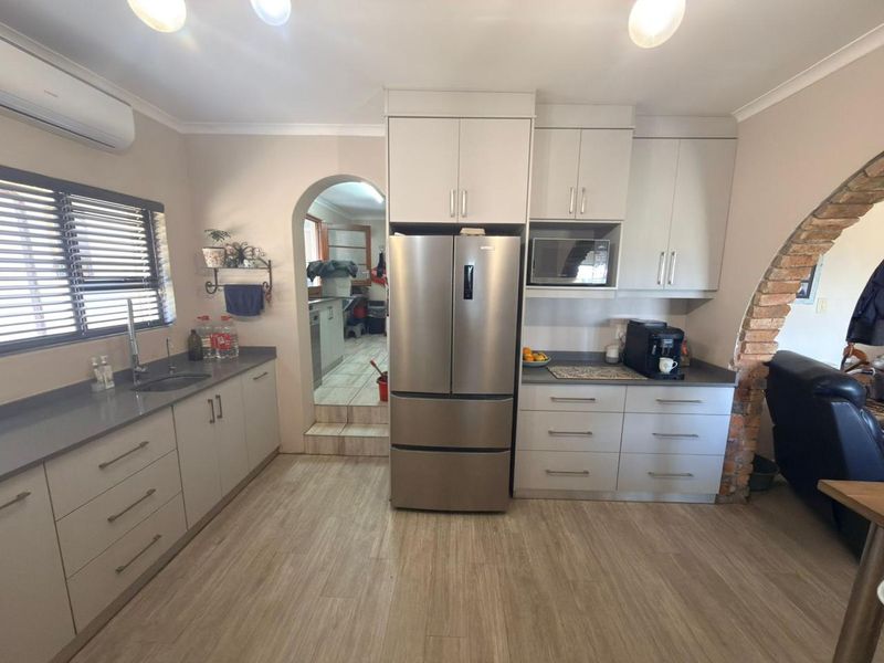 Modern kitchen featuring light-toned cabinetry, stone countertops, integrated microwave, and a functional layout with an adjacent scullery area.