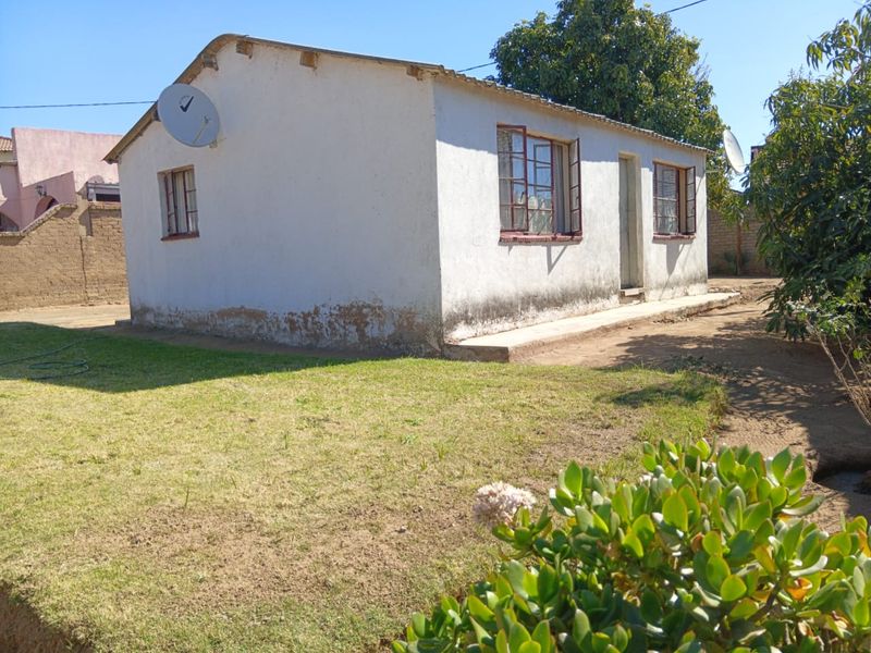 Rear view of a detached house showing exterior walls with visible signs of rising damp and weathered plaster finishes.