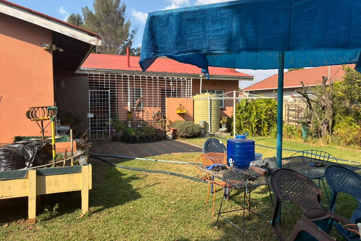 Rear garden area featuring a paved patio, security-fitted windows, and a water storage tank, set against the rear elevation of the house.