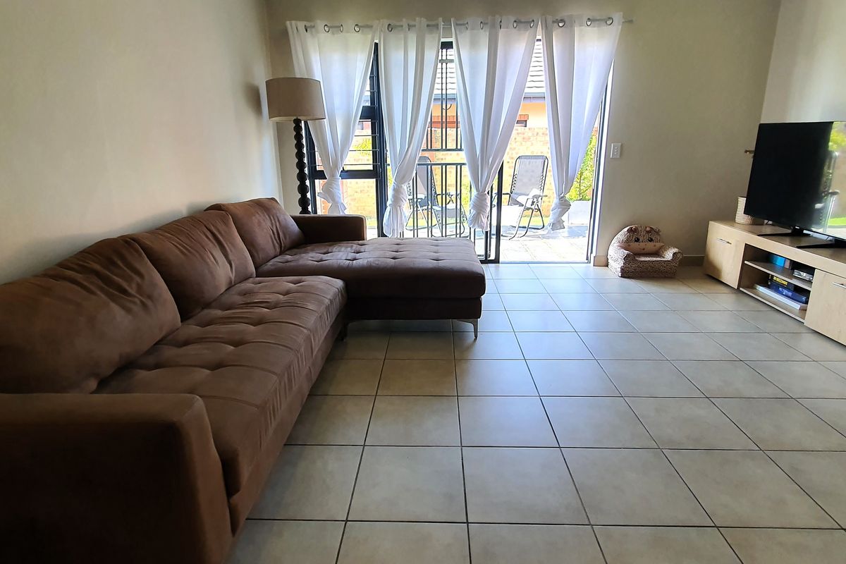 A living room featuring tiled flooring and a sliding glass door providing access to an outdoor patio area.