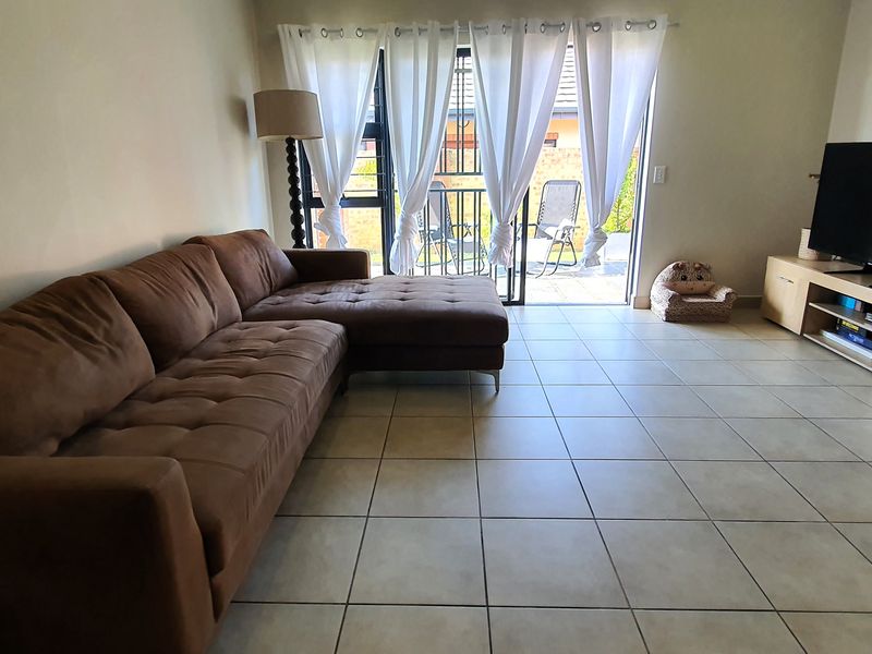 A living room featuring tiled flooring and a sliding glass door providing access to an outdoor patio area.