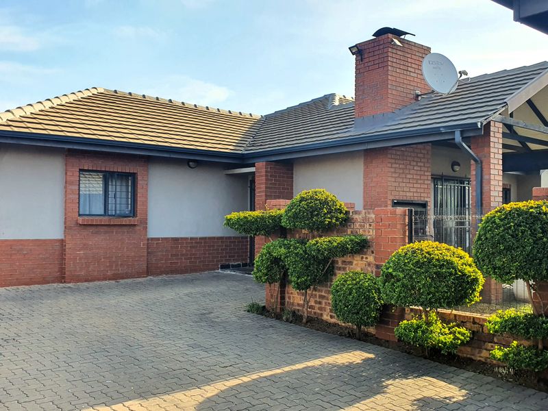 Front elevation of a townhouse featuring a brick facade, tiled roof, paved driveway, and an integrated garage.