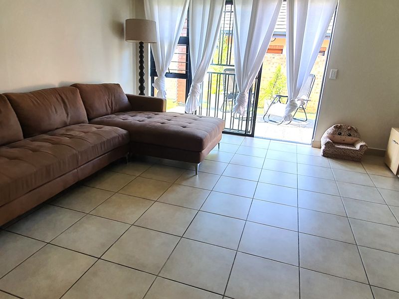 A living room featuring tiled flooring and a sliding glass door providing access to an outdoor patio area.