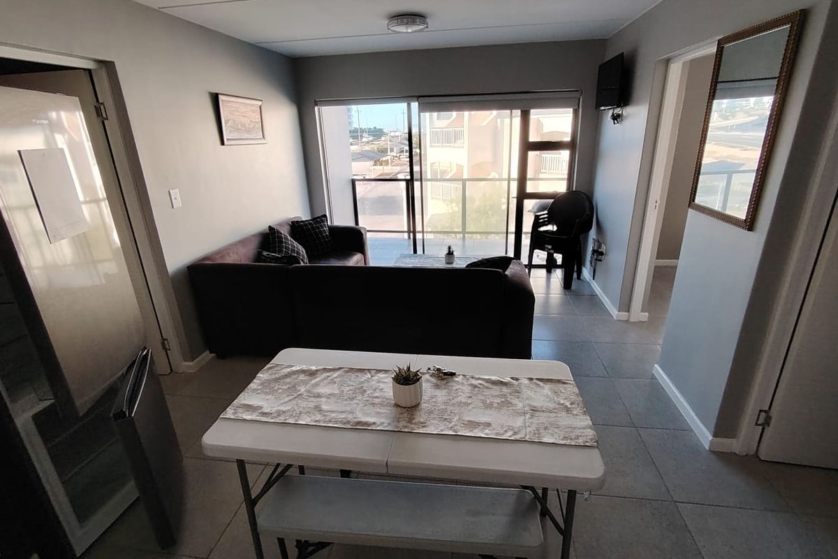 Open-plan living and dining area featuring tiled flooring and a large sliding glass door leading to a balcony.