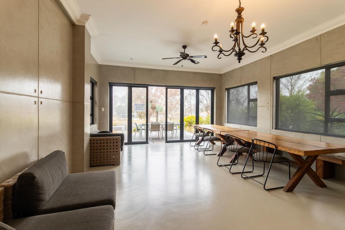 Spacious living area featuring polished concrete floors, modern aluminium sliding doors, and elegant lighting fixtures, offering a seamless transition to the outdoor patio.