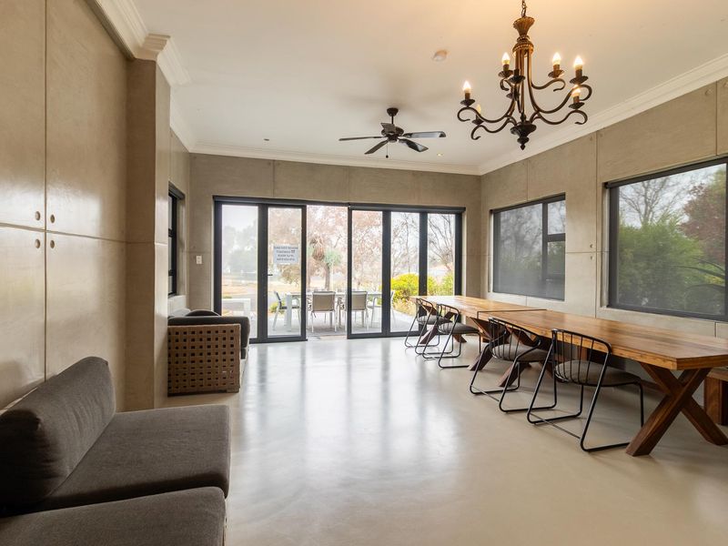 Spacious living area featuring polished concrete floors, modern aluminium sliding doors, and elegant lighting fixtures, offering a seamless transition to the outdoor patio.