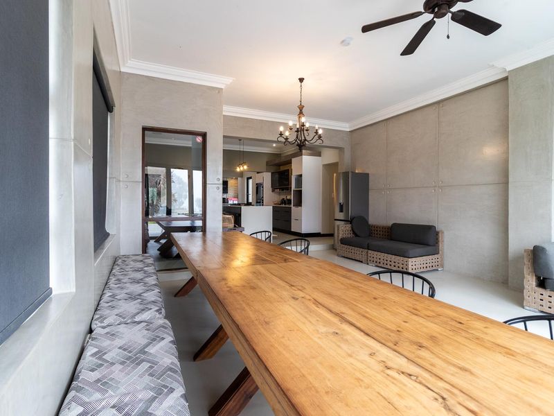 Spacious open-plan living and dining area featuring modern concrete-style wall finishes, a ceiling fan, and a seamless transition into a contemporary kitchen.