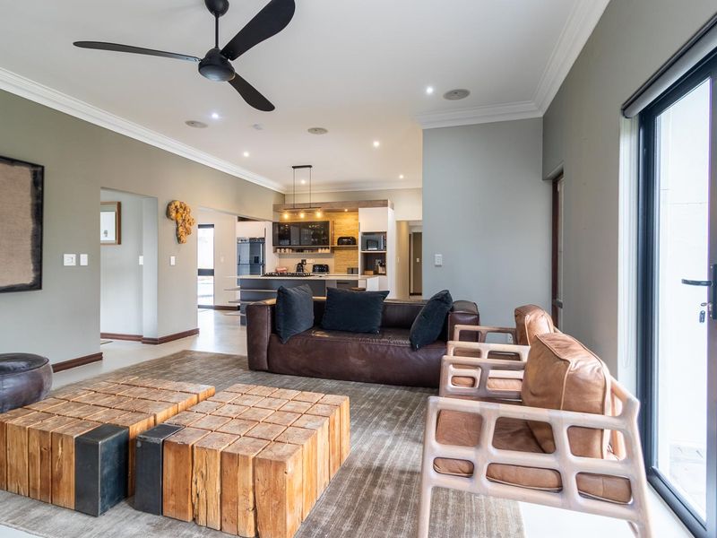 Spacious open-plan living area featuring a modern kitchen with island, recessed lighting, ceiling fan, and large sliding doors leading to the exterior.