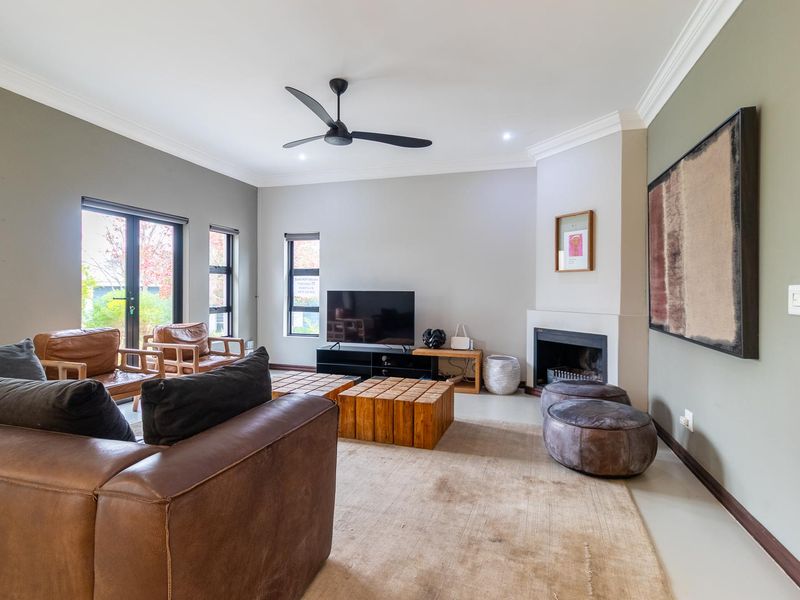 Spacious living room featuring a built-in fireplace, ceiling fan, crown molding, and large windows providing natural light.