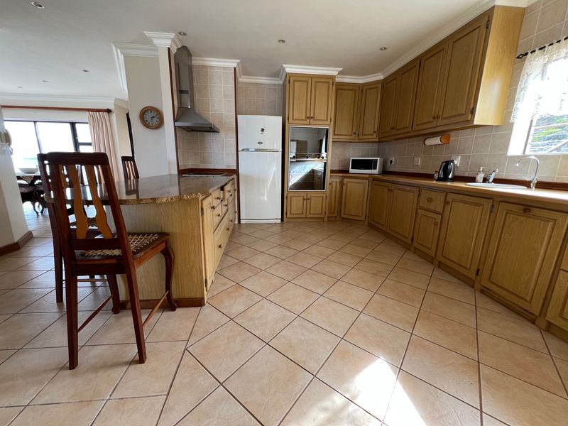 Spacious kitchen featuring traditional oak cabinetry, granite countertops, tiled flooring, and built-in appliances, offering a functional layout with an integrated breakfast bar.