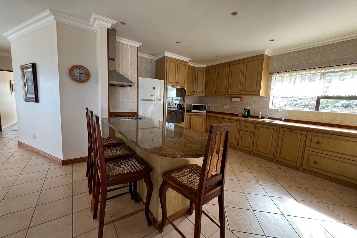 Spacious kitchen featuring wooden cabinetry, granite countertops, a breakfast bar, built-in oven, and tiled flooring with a neutral color palette.