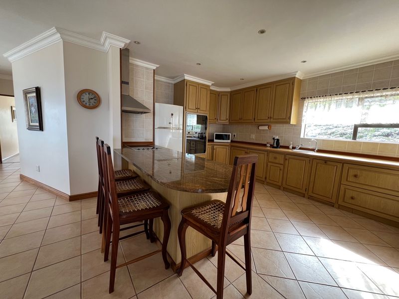 Spacious kitchen featuring wooden cabinetry, granite countertops, a breakfast bar, built-in oven, and tiled flooring with a neutral color palette.