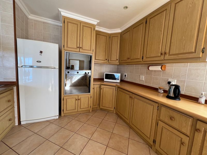 A functional kitchen featuring wood-finish cabinetry, laminate countertops, tiled backsplash, and built-in oven, offering a classic layout with ample storage space.