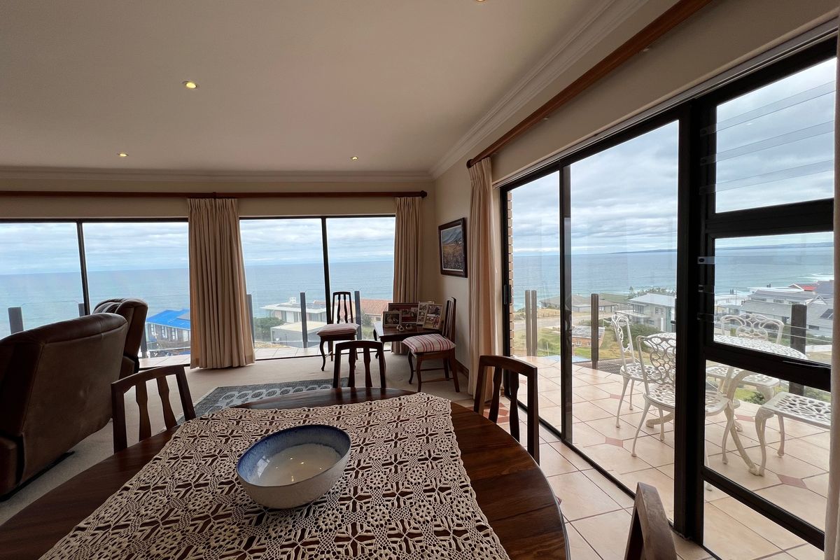 Spacious living area featuring large sliding glass doors that open to a balcony with expansive ocean views and abundant natural light.
