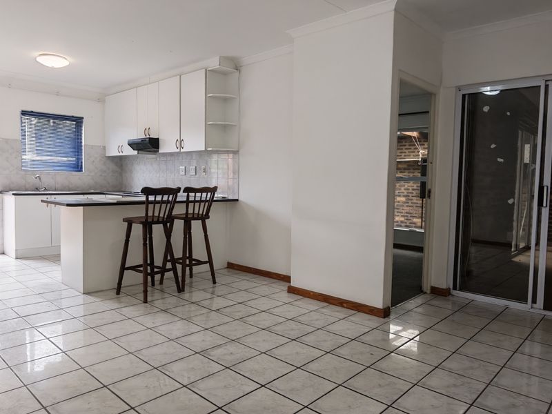 Open plan kitchen and living area featuring tiled flooring, white cabinetry, and sliding glass doors leading to the exterior.