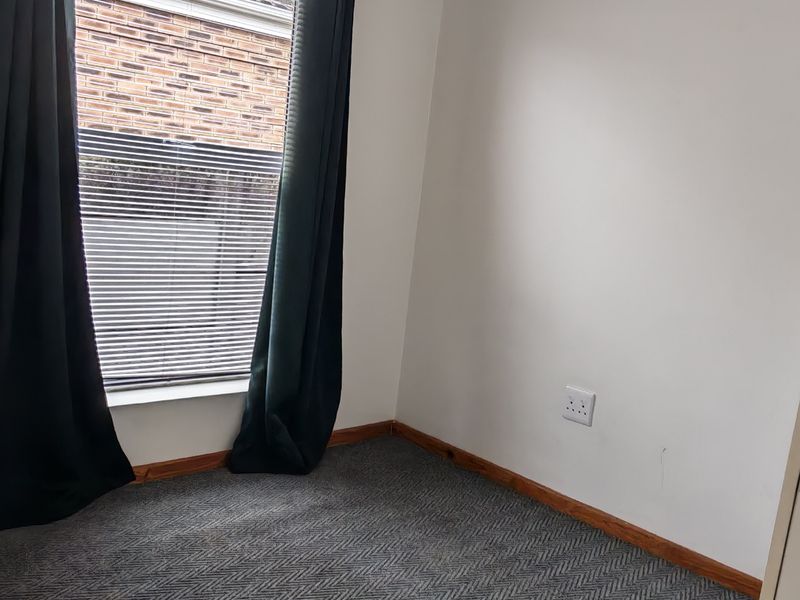 A vacant bedroom featuring a ceiling fan, carpeted flooring, and timber skirting boards, offering a neutral space ready for personalization.