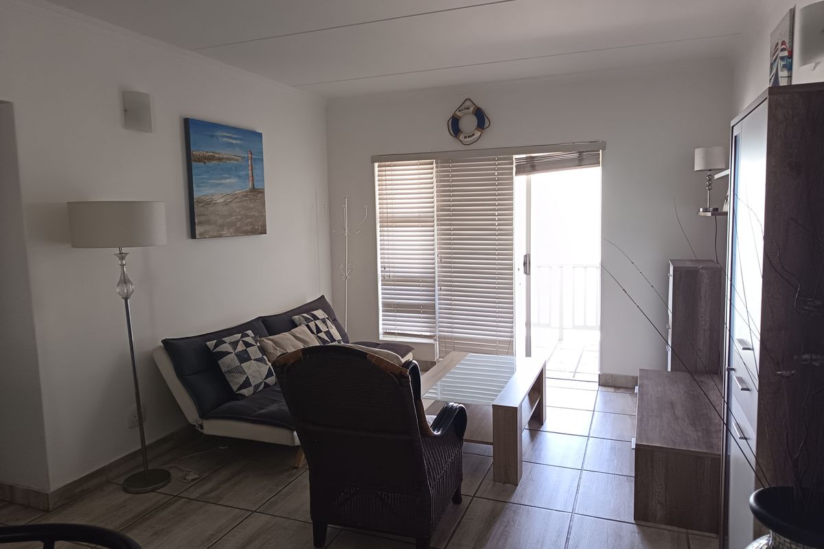 A living room featuring tiled flooring and a sliding door with venetian blinds, providing access to an outdoor area.