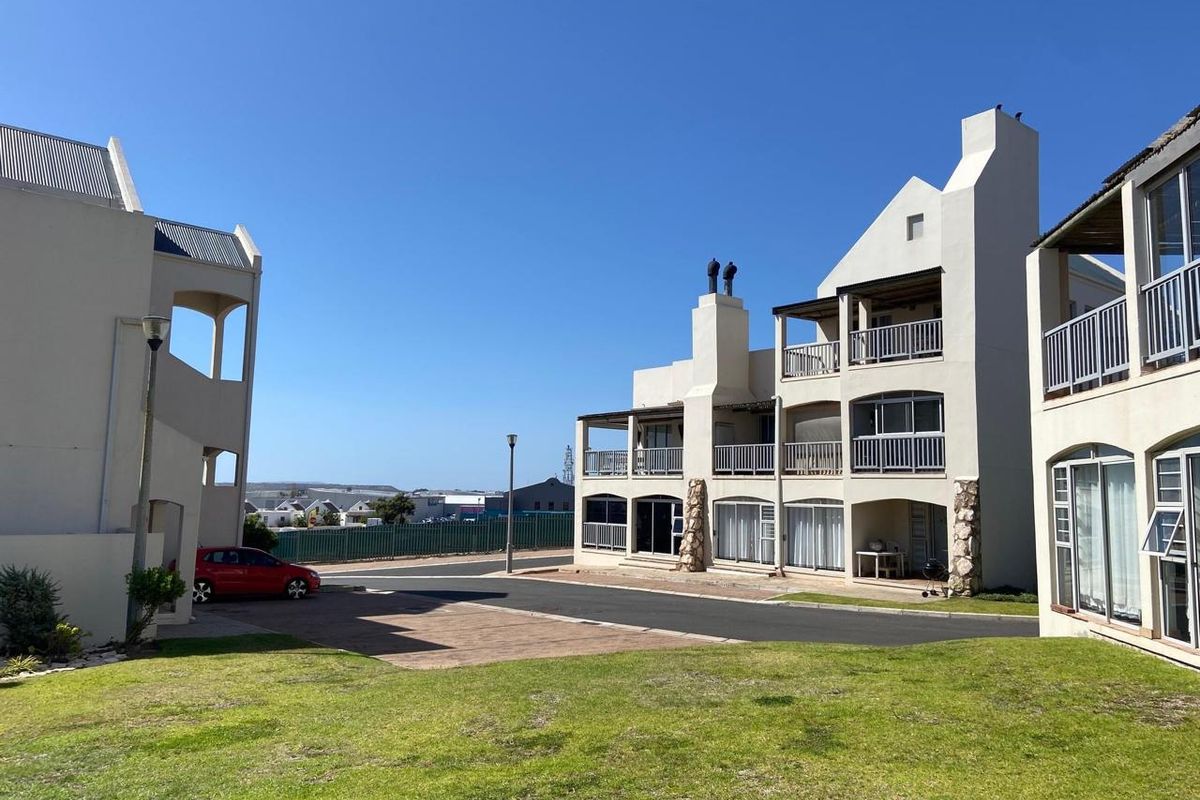 Exterior view of a multi-story apartment complex featuring balconies, paved driveway, and well-maintained lawn areas.