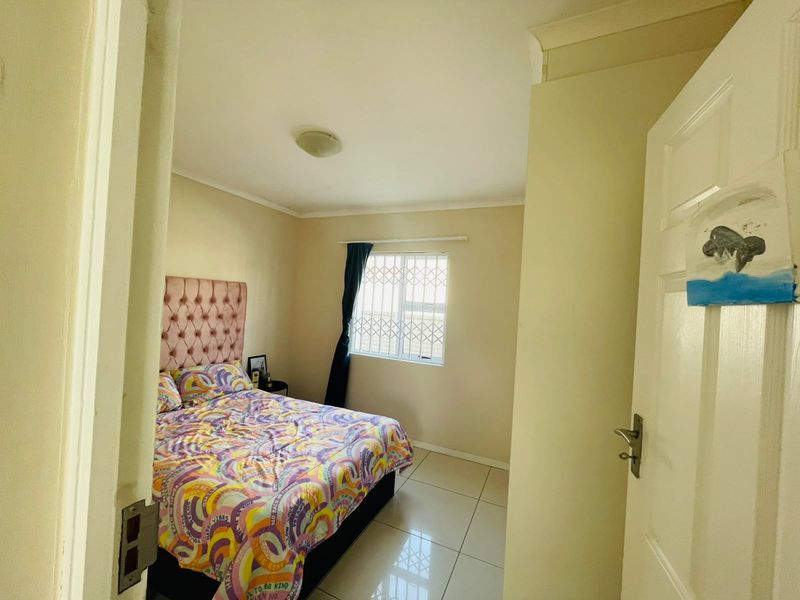 A standard bedroom featuring tiled flooring, a window with a security gate, and neutral wall finishes.