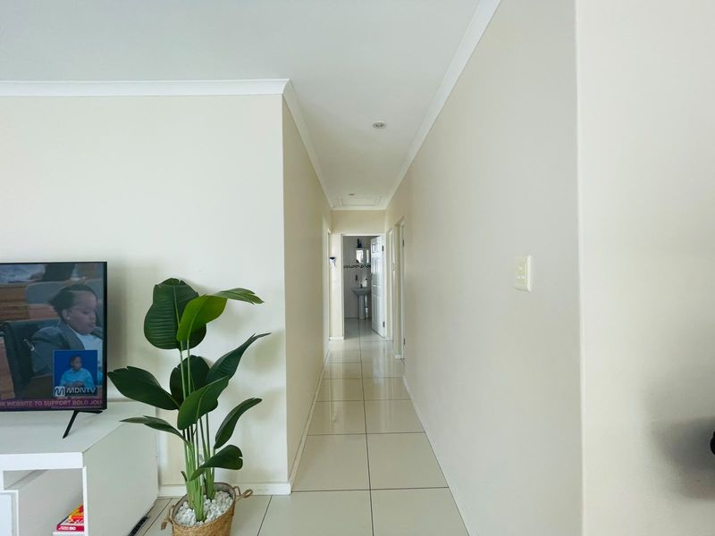 A bright, neutral-toned hallway featuring tiled flooring and recessed lighting, providing access to adjacent rooms within the townhouse.